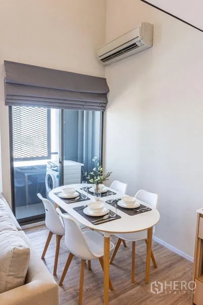 Condominium for rent in Khlong Toei, Bangkok - Bright dining corner for four beside a sliding door to the balcony with washing machine.