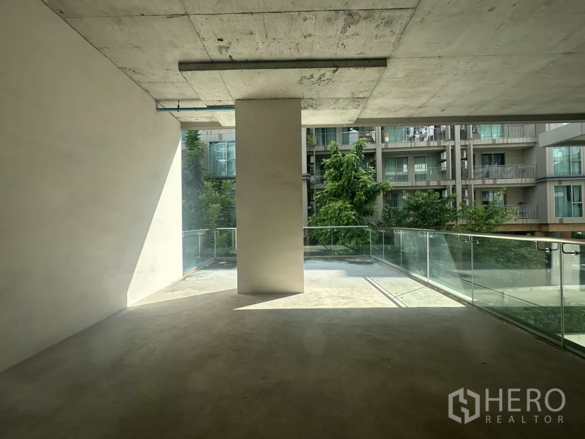 Retail Space for rent - Covered terrace with glass balustrade overlooking nearby residential buildings, suited for café seating.