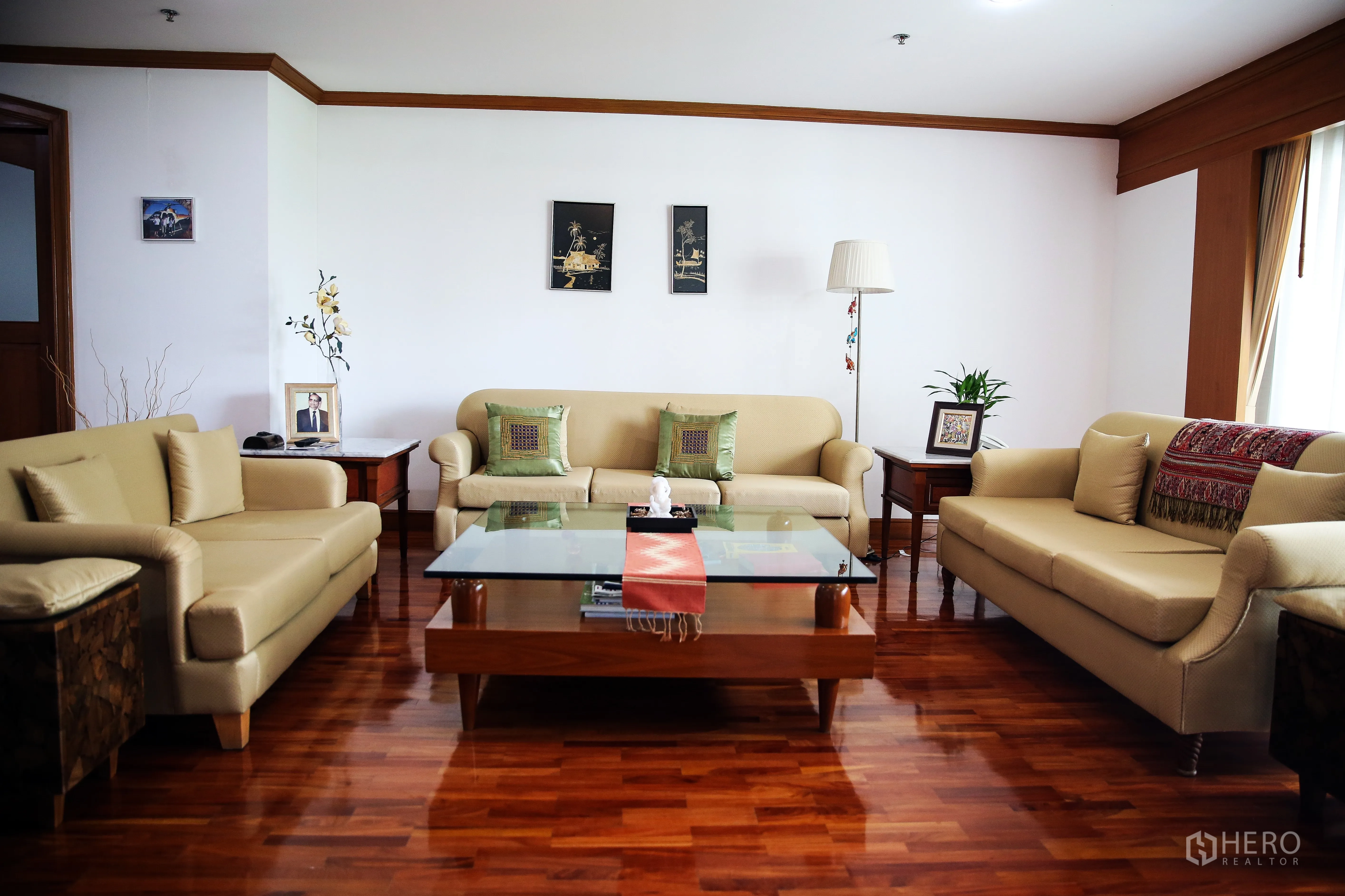 Apartment for rent in Khlong Toei, Bangkok - Cozy living room with three beige sofas around a glass coffee table and wood flooring.