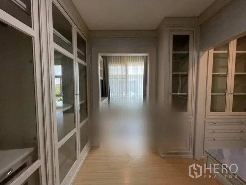 Townhouse for sale in Suan Luang, Bangkok - Walk-through wardrobe corridor with ample storage and natural light from balcony.