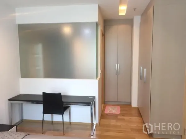 Condominium for rent in Khlong Toei, Bangkok - Study nook with desk and chair beside built-in wardrobes and a frosted glass partition.