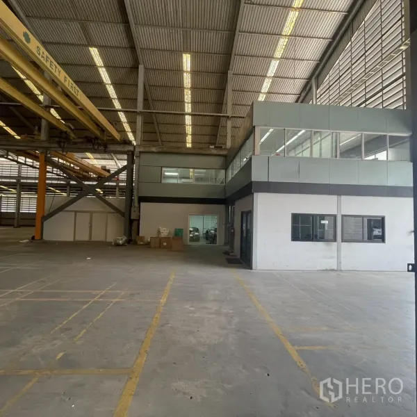 Factory for rent in Khlong Toei, Bangkok - Warehouse hall featuring mezzanine glass office block and safety-marked loading zones.