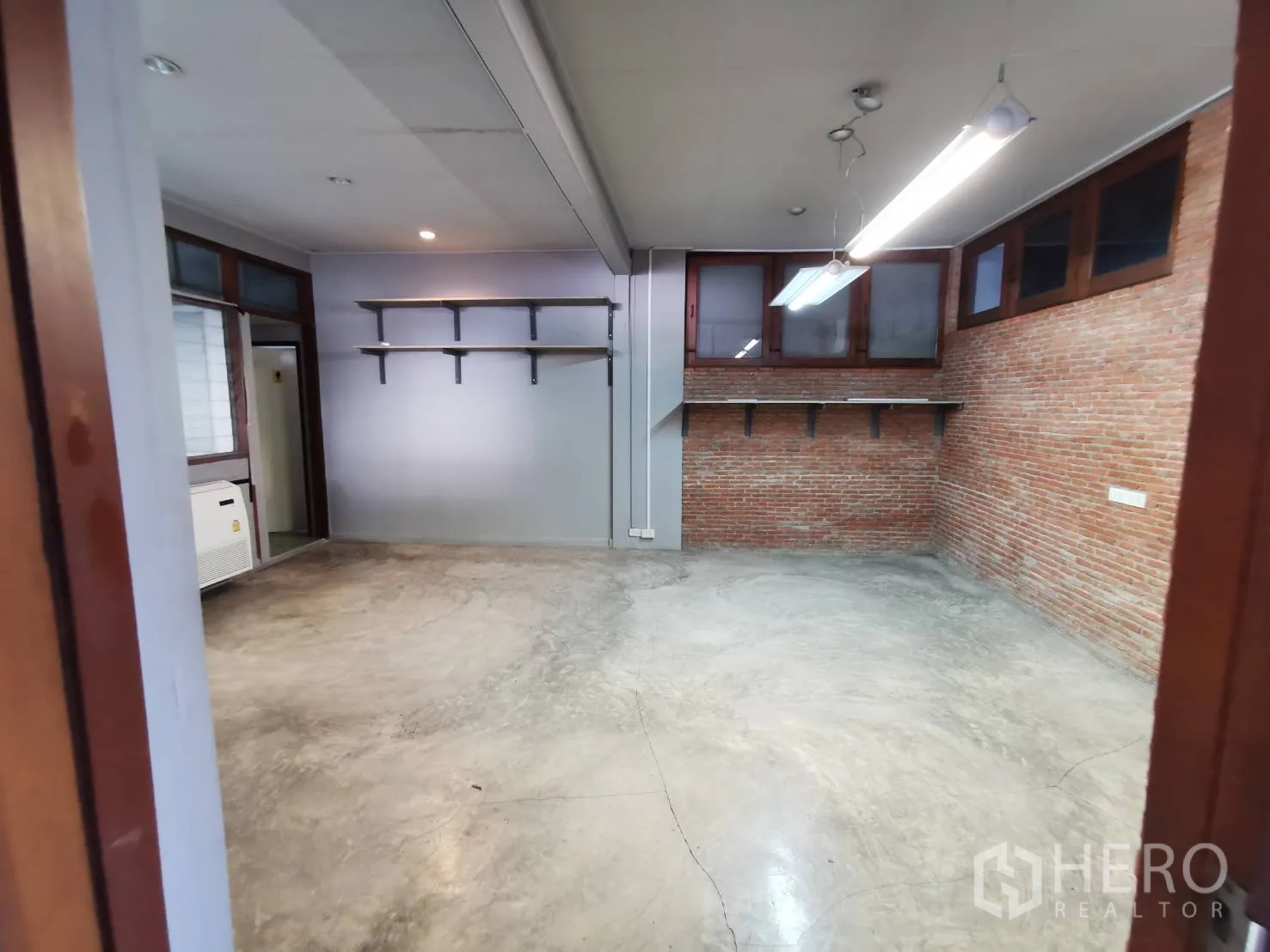 Home Office for rent in Watthana, Bangkok - Workroom with exposed brick walls, built-in shelving and polished concrete flooring.