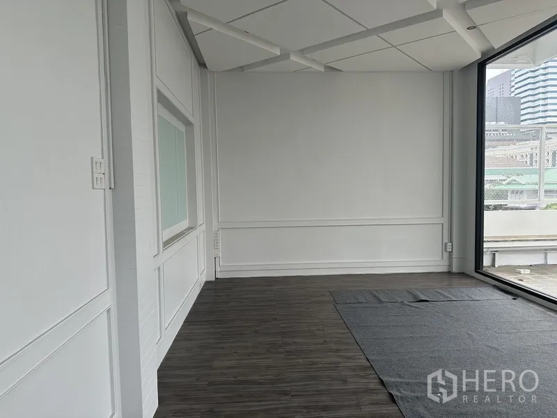Retail Space for rent in Bang Rak, Bangkok - Bright retail room with white walls, dark flooring, and a full-height window to the terrace.