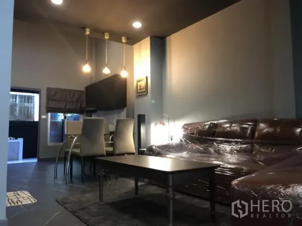 Townhouse for rent in Bang Kapi, Bangkok - Modern open-plan living and dining area with pendant lights, large sofa and coffee table.