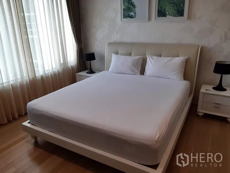Condominium for rent in Khlong Toei, Bangkok - Sunlit bedroom with a queen bed, bedside tables and floor-to-ceiling curtains.
