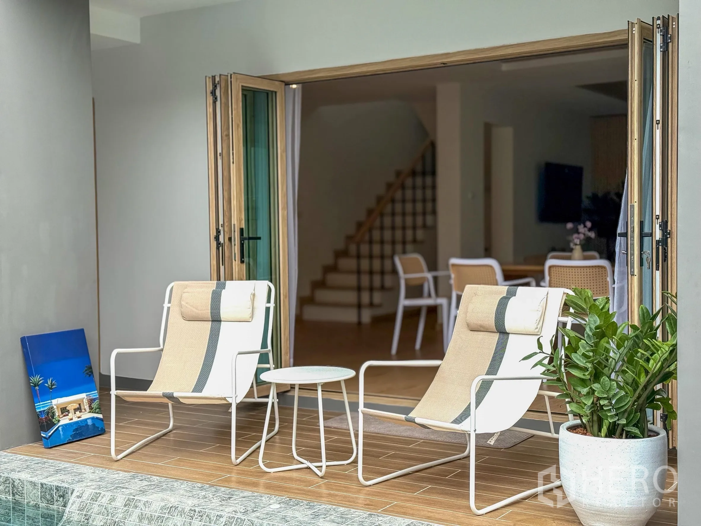 Detached House for sale in Suan Luang, Bangkok - Poolside patio with two lounge chairs and wide folding doors opening to the living area.