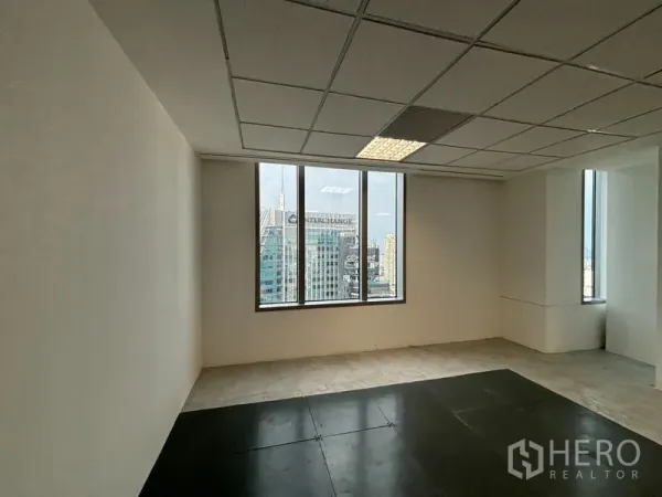 Office Space for rent in Watthana, Bangkok - Corner office area with large windows framing the Bangkok skyline and suspended ceiling panels with bright lighting.