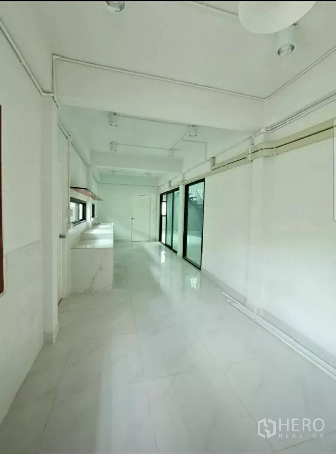 Home Office for rent in Lat Phrao, Bangkok - Long galley pantry with white counters, sliding glass to the yard and ceiling lights.