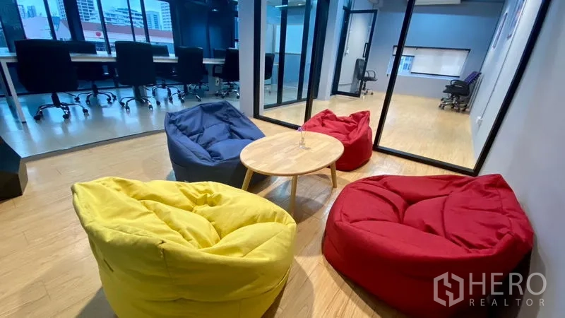 Office Space for rent in Sathon, Bangkok - Colorful beanbag lounge with a round coffee table beside glass-partitioned offices in a modern workspace.