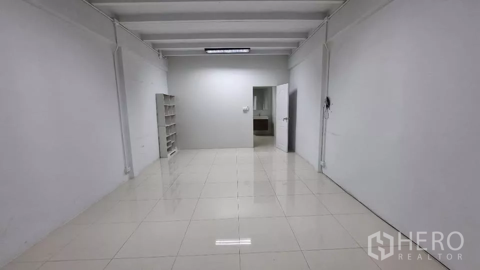 Townhouse for rent in Huai Khwang, Bangkok - Large multipurpose room with shelving and a doorway to a bathroom.