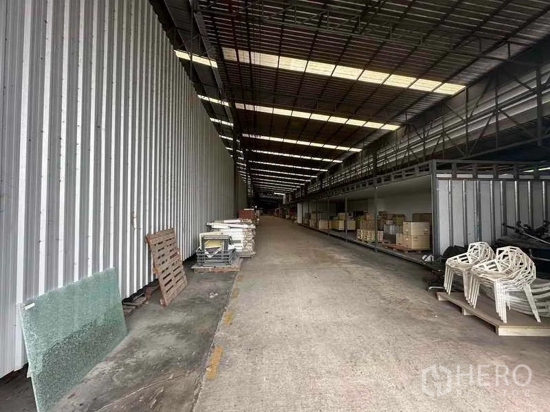 Factory for rent in Pathum Thani - Covered service corridor with long roof and materials stored on pallets on both sides.
