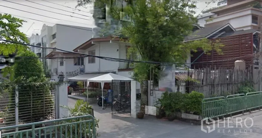 Retail Space for rent in Watthana, Bangkok - Street view of a low-rise retail building with gated entrance, greenery and neighboring homes in the Sukhumvit 31 area.