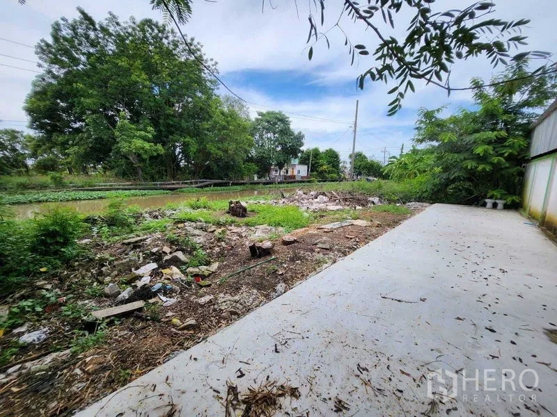 Warehouse for rent in Lat Krabang, Bangkok - Rear yard with concrete apron beside a canal and mature trees.