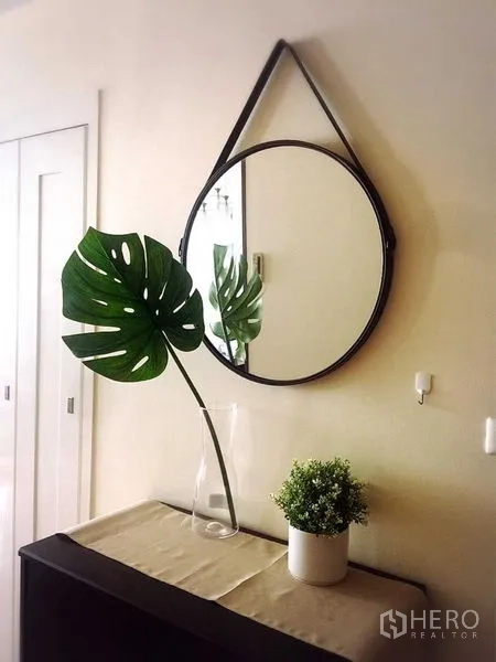 Condominium for rent in Khlong Toei, Bangkok - Entry console with round hanging mirror and decorative green plants.