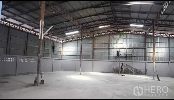 货栈 出租在Sai Noi, Nonthaburi - 开阔的仓库内部，钢架屋顶与照明
