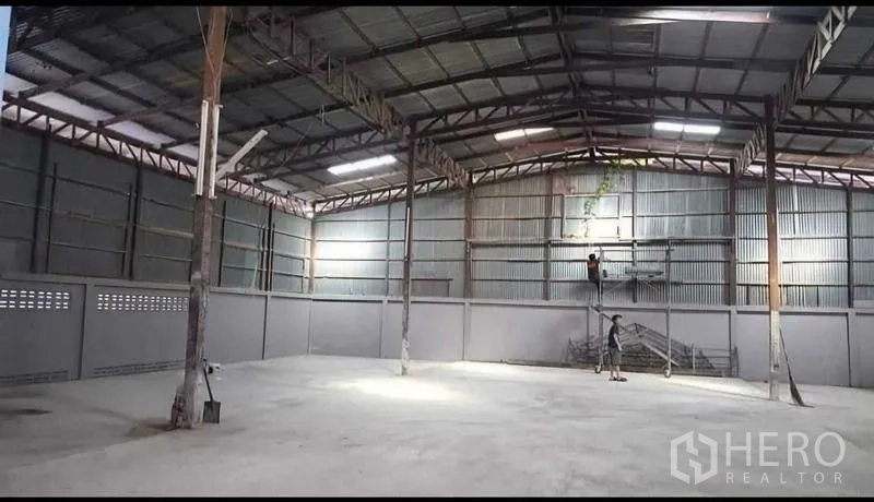 货栈 出租在Sai Noi, Nonthaburi - 开阔的仓库内部，钢架屋顶与照明