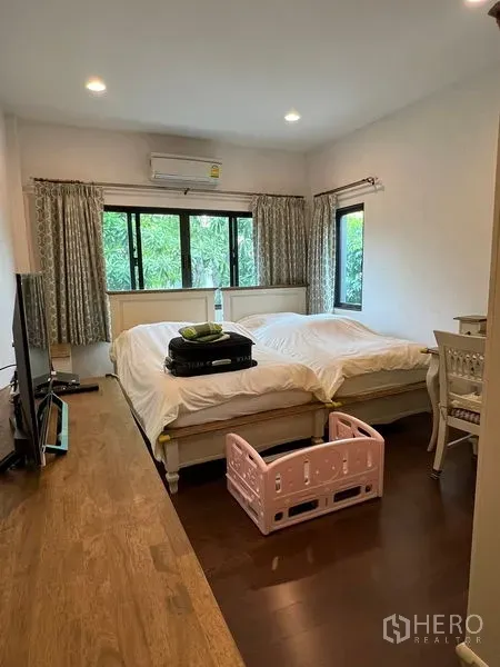 Detached House for sale in Bang Kapi, Bangkok - Airy bedroom with large windows, twin-bed layout and warm wood flooring.