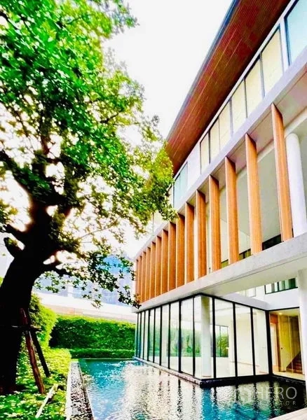 Detached House for sale in Huai Khwang, Bangkok - Modern house exterior with vertical wood fins above a pool and a mature tree.
