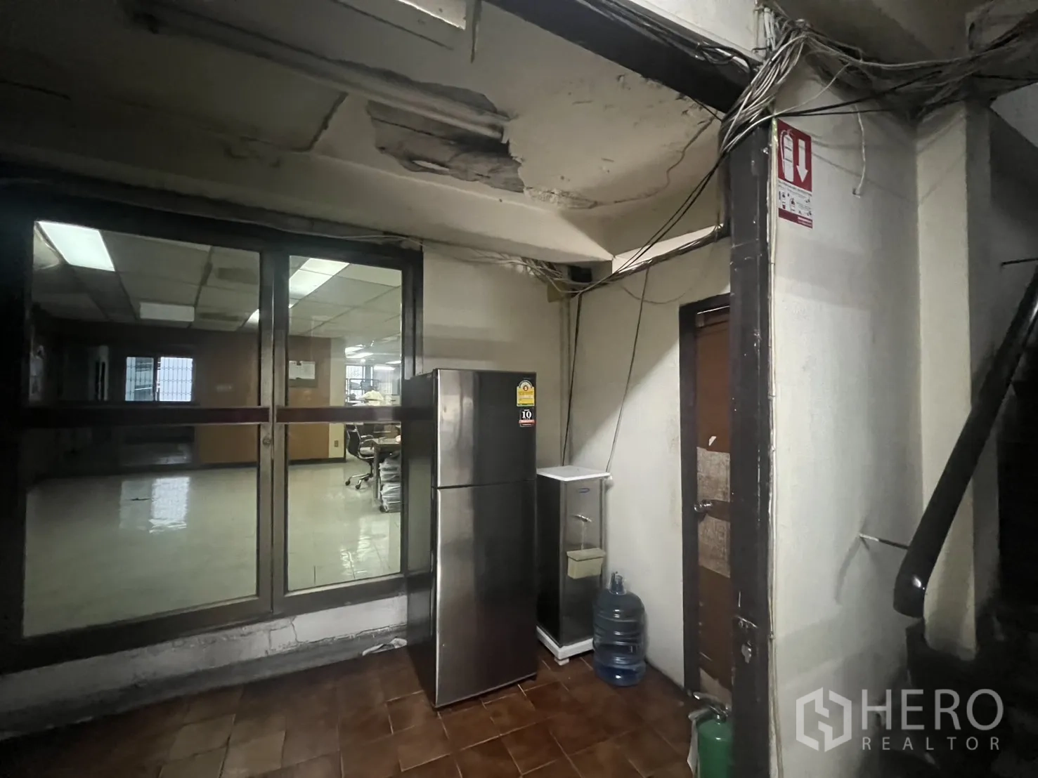 Shophouse for rent - Rear service area with glass door, fridge and exposed ceiling.