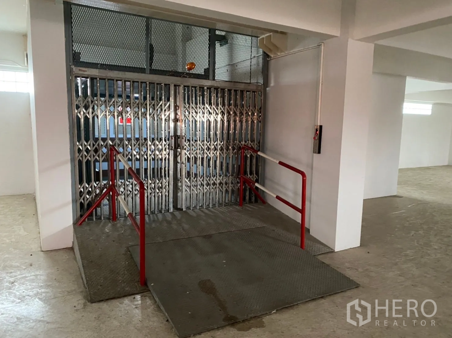 Warehouse for rent in Lat Krabang, Bangkok - Cargo lift platform with ramp and red safety rails inside the warehouse.