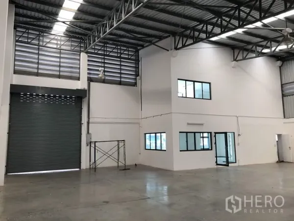 Warehouse for rent or sale in Lam Luk Ka, Pathum Thani - Spacious warehouse interior with high steel truss roof, big shutter door and built-in office rooms with windows.