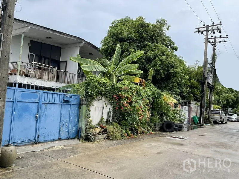 Detached House for sale in Khlong Toei, Bangkok - Two-storey detached house with balcony, blue metal gate and lush vines on a quiet Phra Khanong lane.