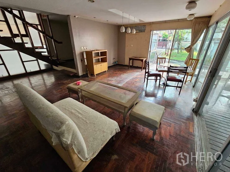 独立式住宅 出租在Sathon, Bangkok - 一层起居室，带楼梯和面向花园的大窗。