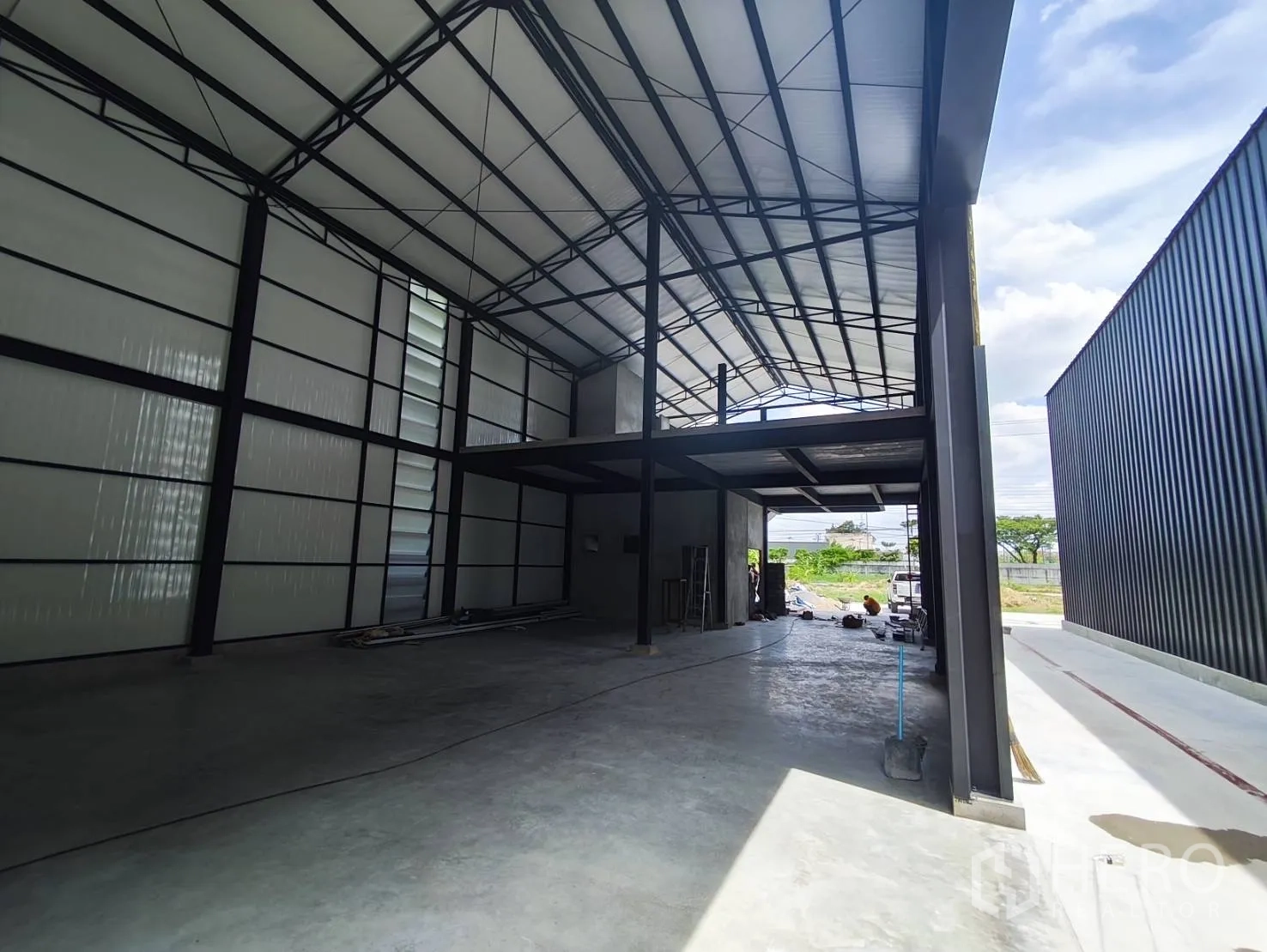 Warehouse for rent in Sai Mai, Bangkok - Open-plan warehouse interior showing a partial mezzanine and wide entrance.