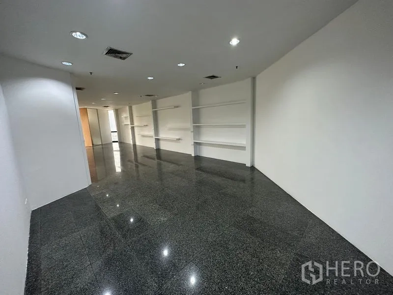 Office Space for rent - Spacious open office with recessed lighting, built-in wall shelving and reflective floors.