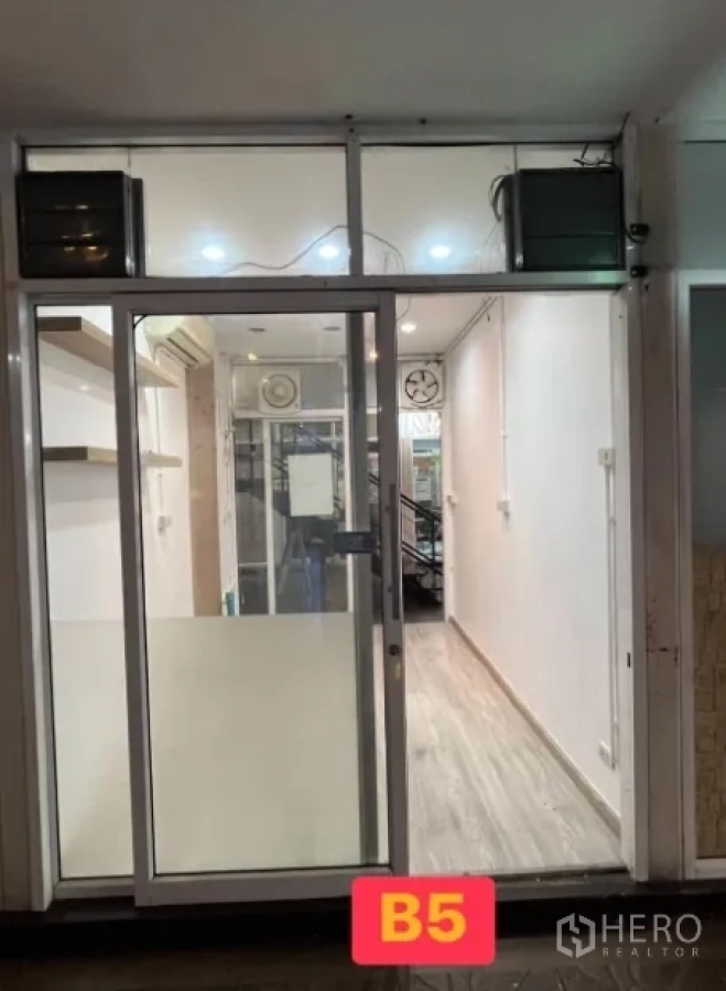 Retail Space for rent in Watthana, Bangkok - Compact retail unit with glass sliding door, bright ceiling lights, and light wood flooring, labeled B5.