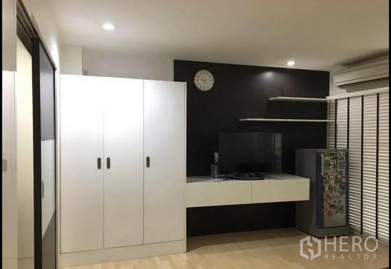 Townhouse for sale in Khlong Toei, Bangkok - Media wall with floating TV console, white wardrobes, shelves and air conditioner.