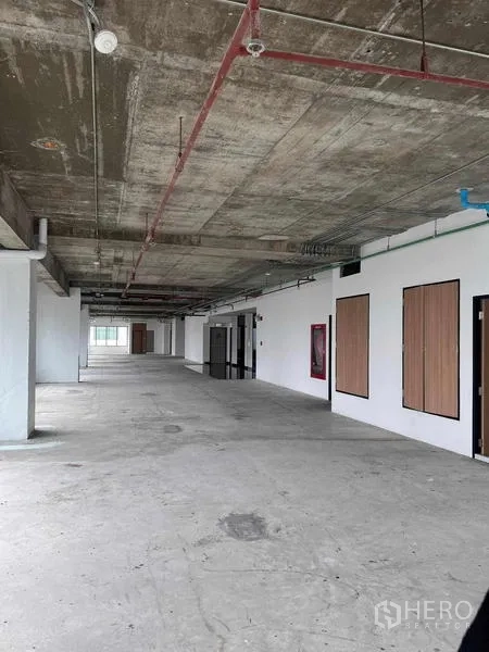 Office Space for rent in Watthana, Bangkok - Wide corridor-style office area with exposed ceiling, white walls and several service doors.