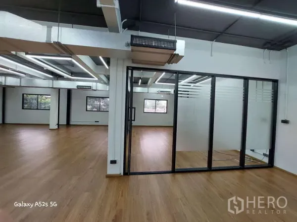 Office Space for rent in Khlong Toei, Bangkok - Bright open-plan office with wood floors, a glass-partitioned meeting room and large windows.