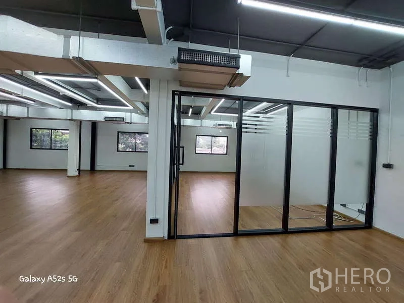 Office Space for rent in Khlong Toei, Bangkok - Bright open-plan office with wood floors, a glass-partitioned meeting room and large windows.