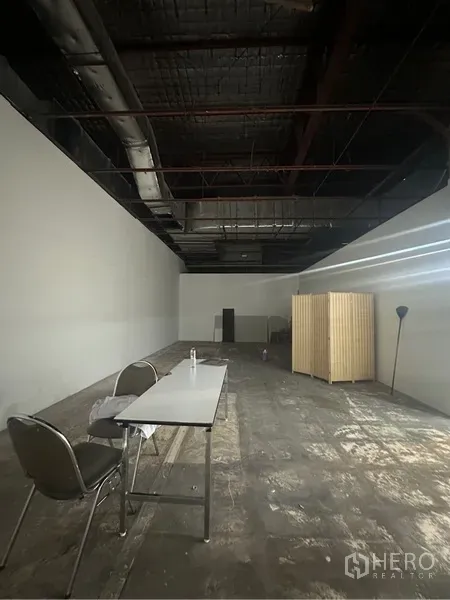 Retail Space for rent - Deep open-plan retail interior with high exposed ceiling, ducting, and unfinished flooring.
