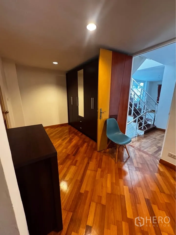 Townhouse for rent in Huai Khwang, Bangkok - Hallway with wardrobes, polished wooden flooring and stair access.
