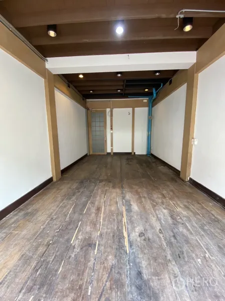 Shophouse for rent - Upper-floor room with exposed beams, white walls and worn wooden floorboards.