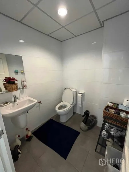 Home Office for rent in Bang Rak, Bangkok - Bright tiled bathroom with toilet, basin and mirror.
