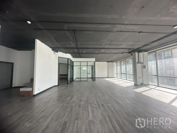 Office Space for rent in Khlong Toei, Bangkok - Long open office floor with perimeter windows, wiring trays, and an industrial ceiling.