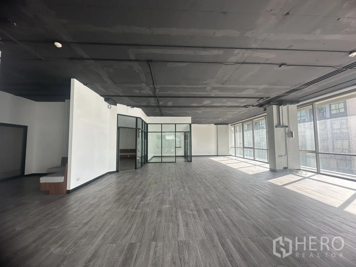 Office Space for rent in Khlong Toei, Bangkok - Long open office floor with perimeter windows, wiring trays, and an industrial ceiling.