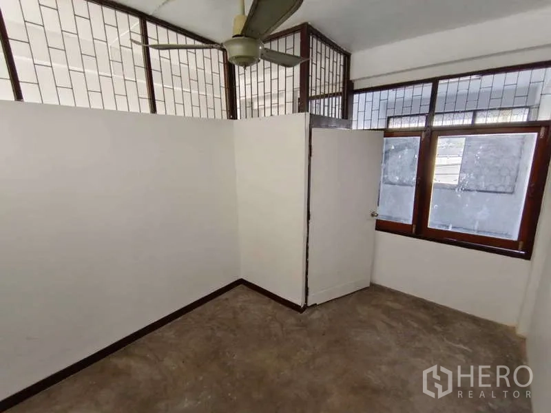 Shophouse for rent in Bang Na, Bangkok - Compact partitioned room with ceiling fan and glass windows.