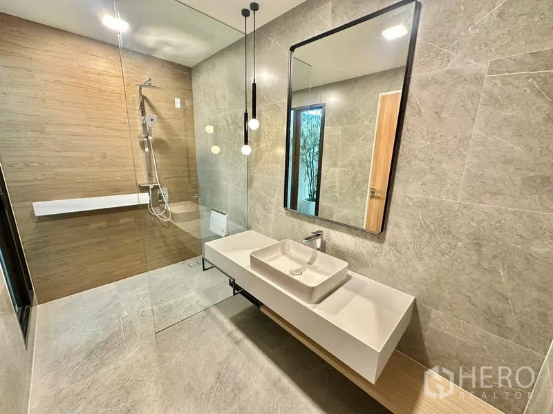 Detached House for rent in Samut Prakan - Contemporary bathroom with glass shower, floating vanity and a large mirror.