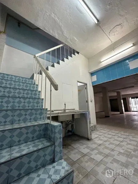 Shophouse for rent in Bang Na, Bangkok - Tiled staircase with handrail leading to upper floors and a small service counter.