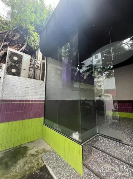 Retail Space for rent in Watthana, Bangkok - Side exterior close-up of glass corner display with green and purple tiled base and entry steps.