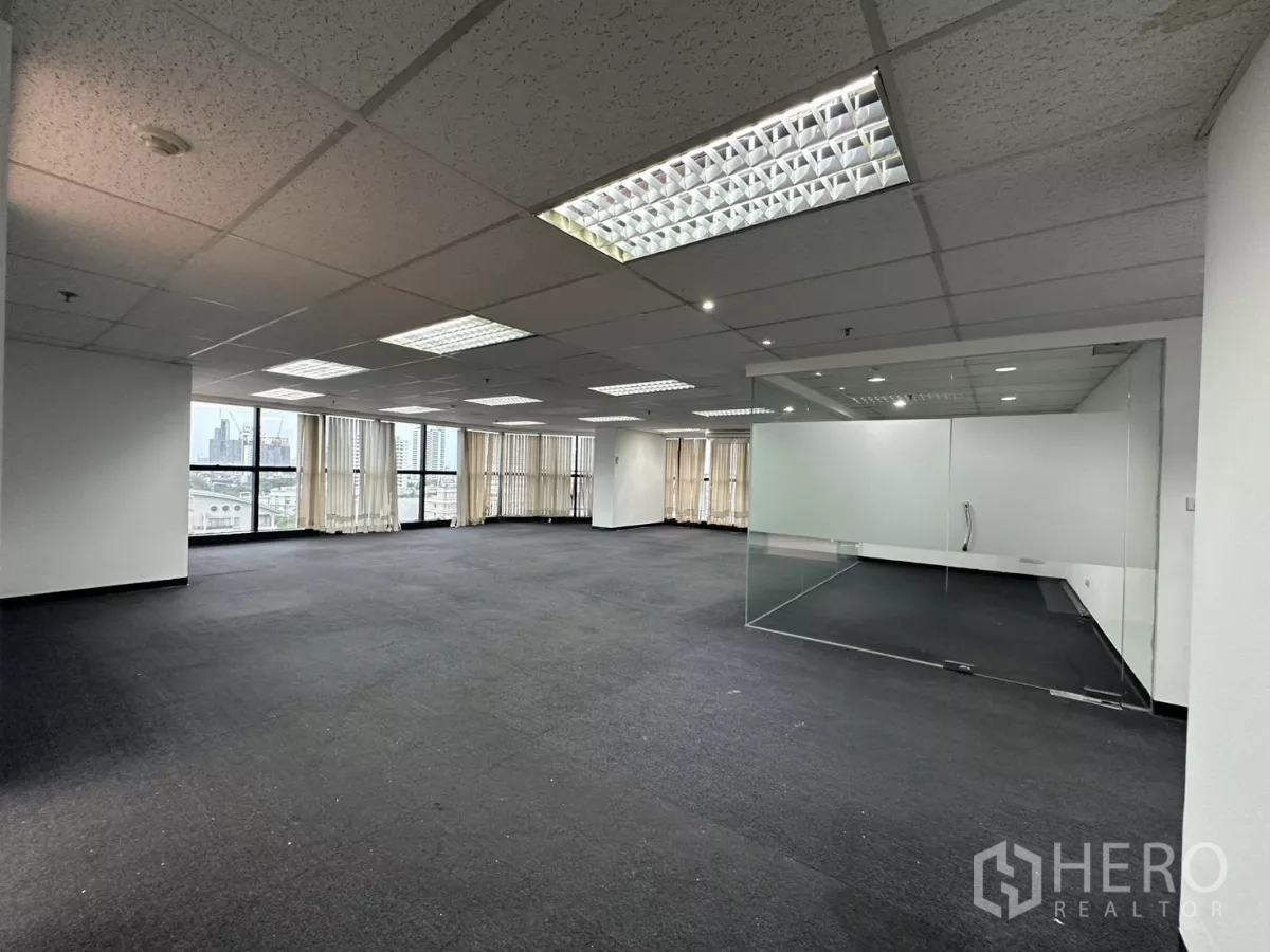 Office Space for rent in Watthana, Bangkok - Large open office with vertical-blind windows, fluorescent lighting, and a glass-walled meeting room.