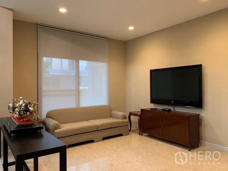 Detached House for rent or sale in Khan Na Yao, Bangkok - Cozy TV room with wall-mounted screen, sofa and cabinet.