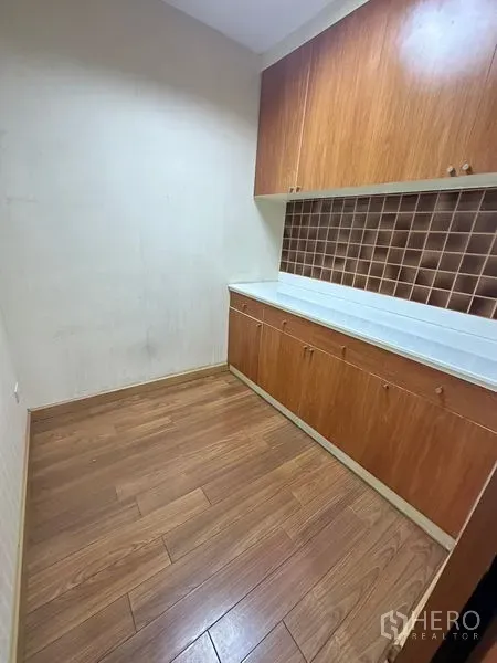 Office Space for rent - Compact pantry with upper and lower wooden cabinets, countertop and wood flooring.