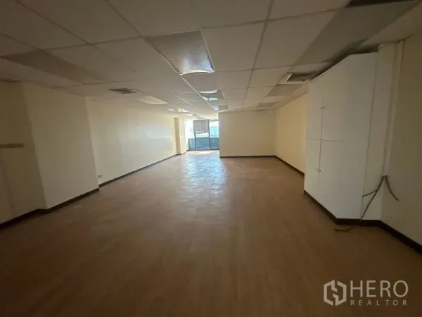 办公空间 出租 - 开放式办公区，木纹地板、吊顶照明，内置柜体与尽端窗户。