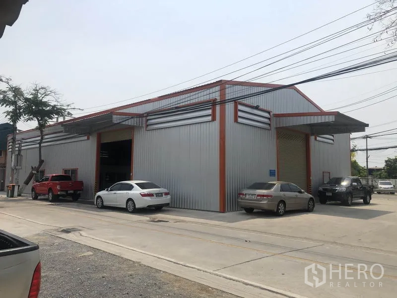 货栈 出租在Bang Yai, Nonthaburi - 现代金属板仓库外观，临宽阔混凝土路面并配有多处停车位。